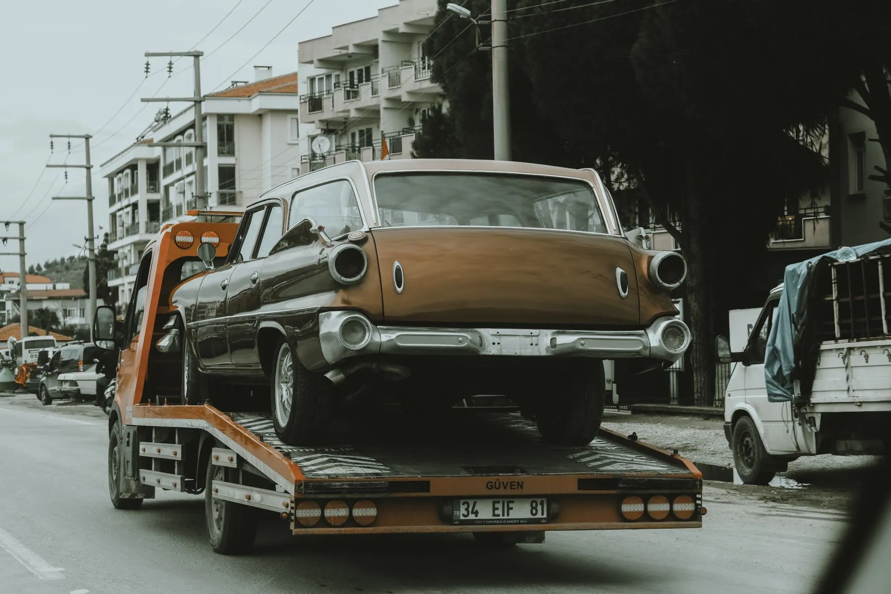 Una grúa lleva un carro viejo por una calle de la ciudad